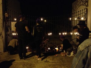 Laying candles along the closed cemetery gates.